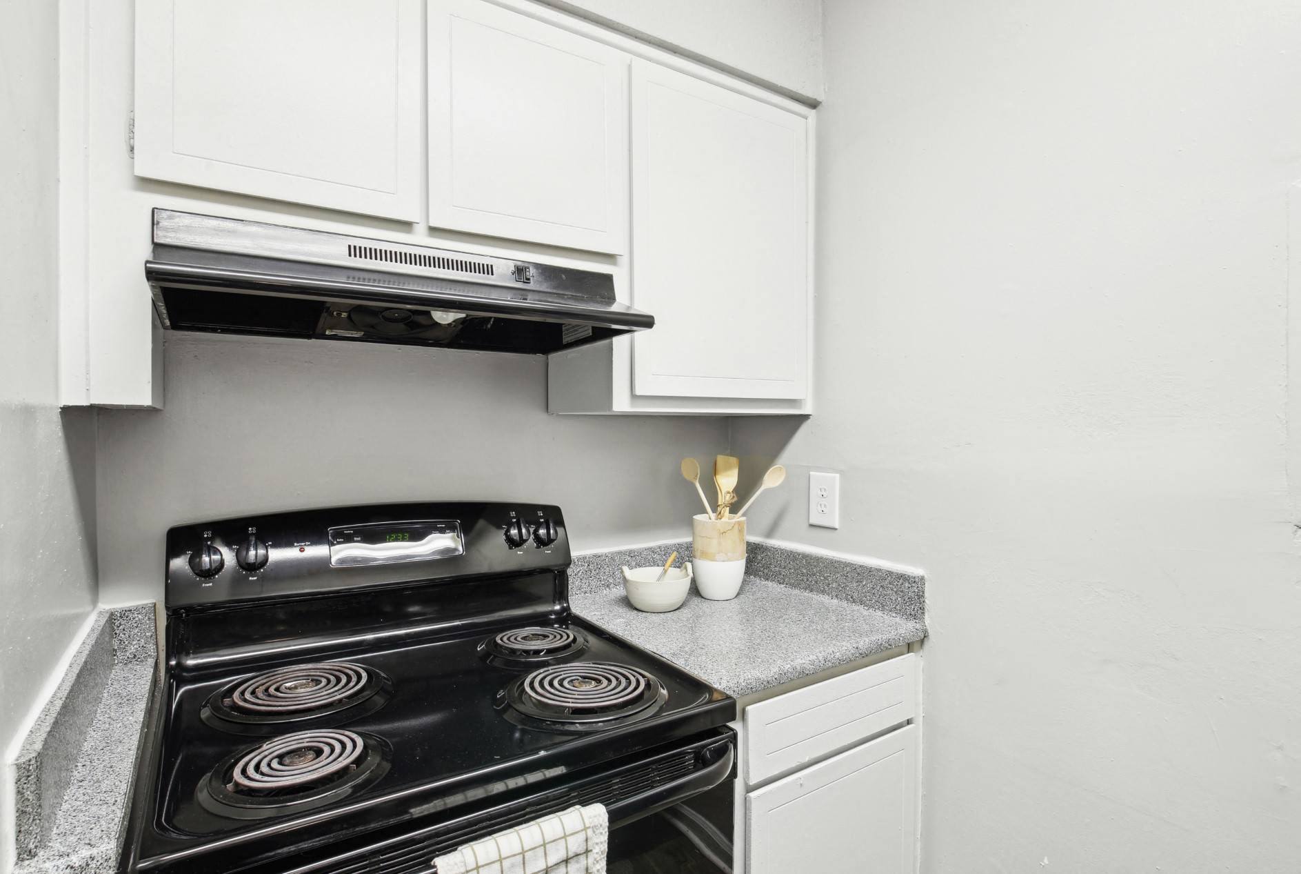 a kitchen with white cabinets and a black stove